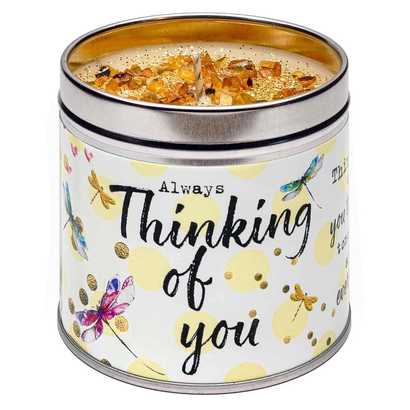A tin candle with a floral and butterfly pattern, labeled 'Thinking of you', with a lit wick inside.