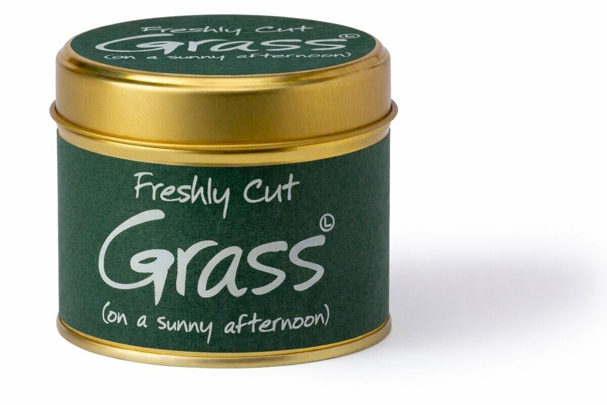 Candle tin labeled 'Freshly Cut Grass on a sunny afternoon' with green and gold design.
