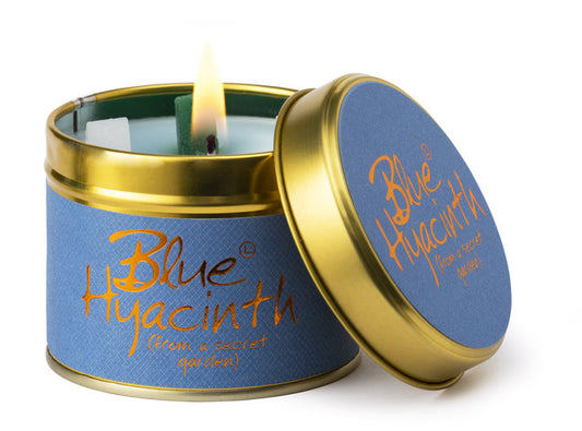 Blue Hyacinth candle in a tin with a lit wick on a white background