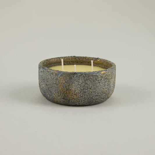 Ceramic bowl with a candle inside on a plain background