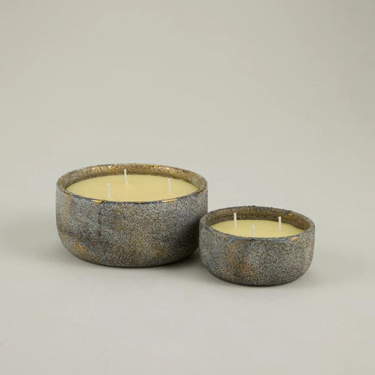 Two rustic ceramic candle holders with candles on a light gray background