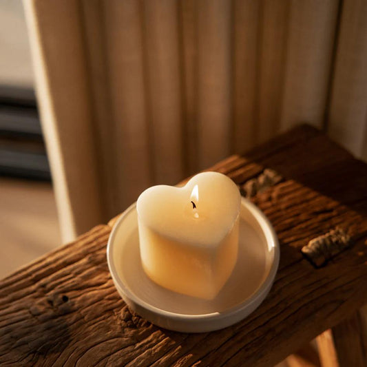 Heart-shaped candle on a wooden surface with a blurred background