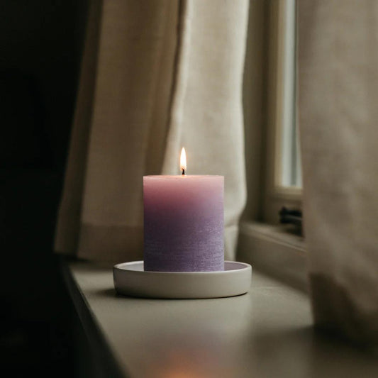 Purple candle on a white plate with a blurred background