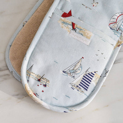 Pair of oven mitts with sailboat pattern on a light background