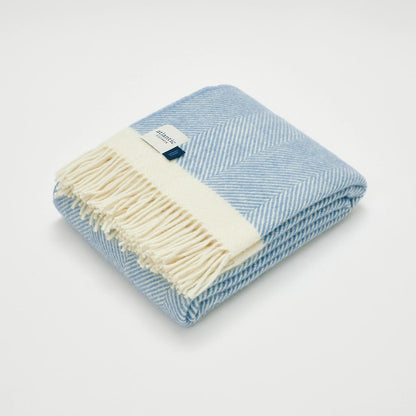 Folded blue and white checkered blanket with a visible brand tag on a light gray background