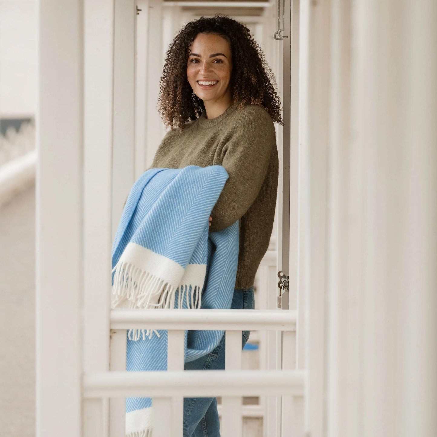 Woman holding a blue and white blanket in a neutral setting