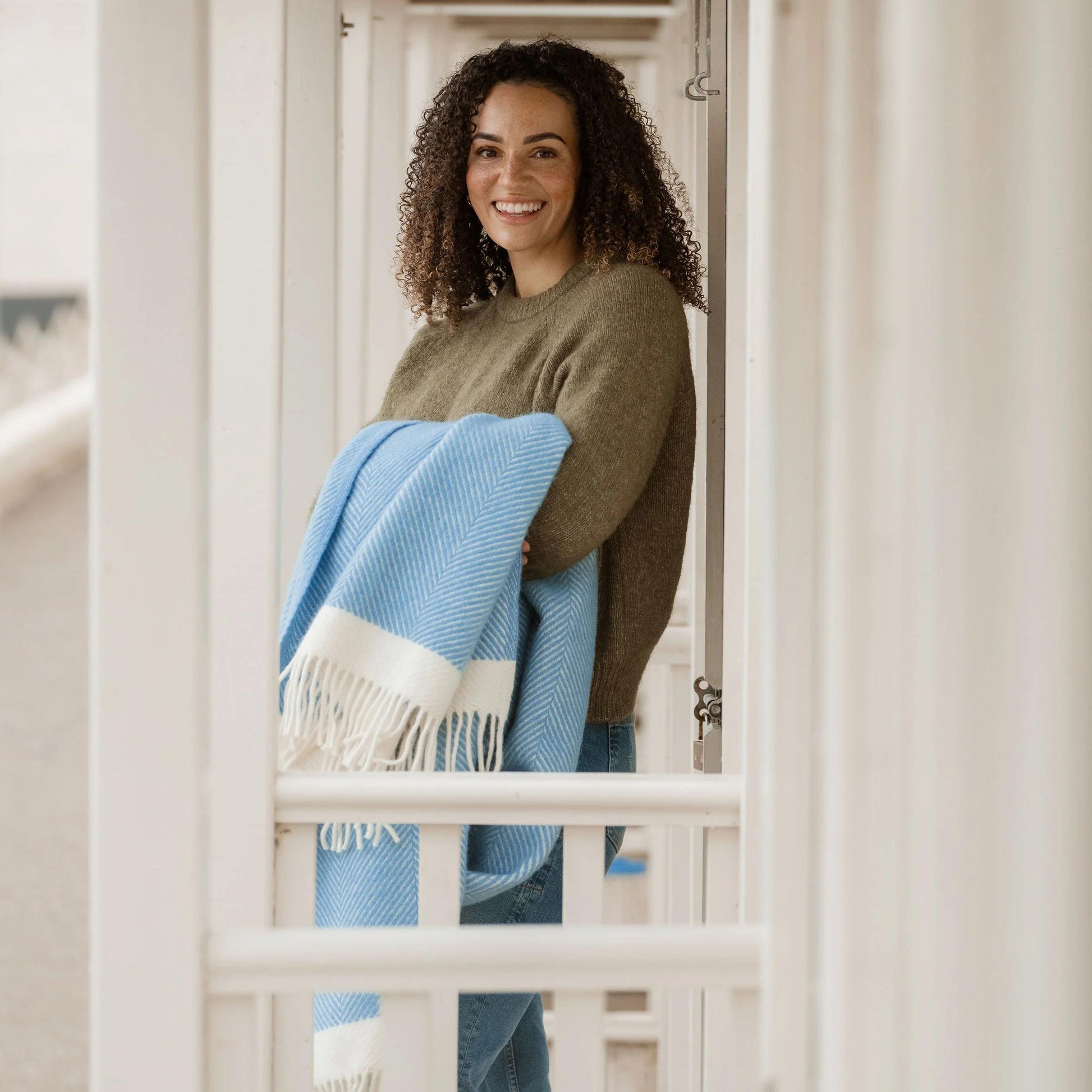 Woman holding a blue and white blanket in a neutral setting