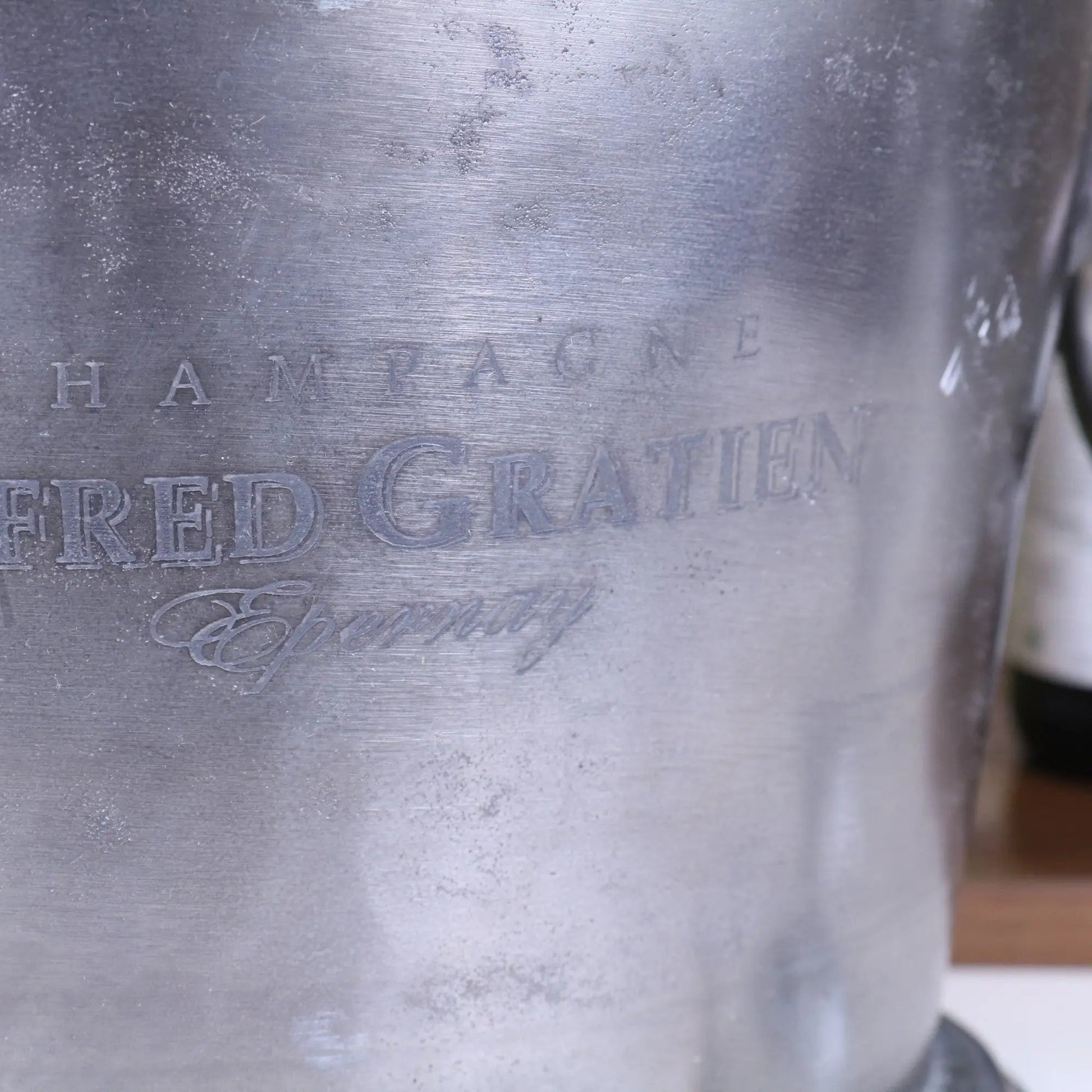 Metallic champagne bucket with 'FRED GRATIEN' branding.