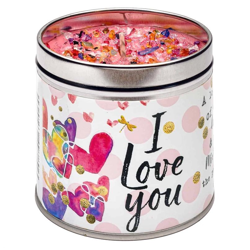 A tin candle with a multicolored wax melt visible through the transparent lid, featuring a 'I love you' message and heart illustrations on the label.