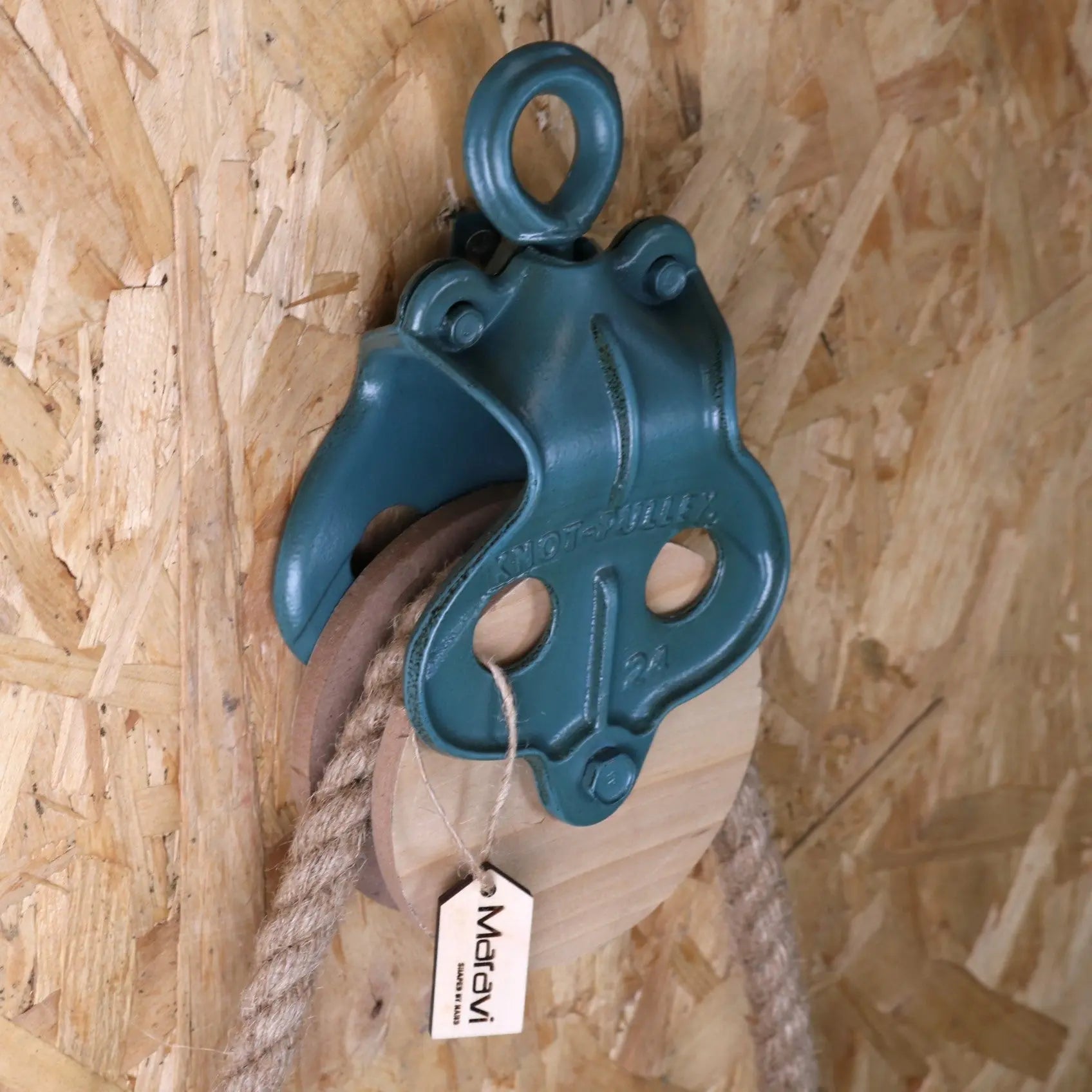 Teal pulley system attached to a rope on a wooden background