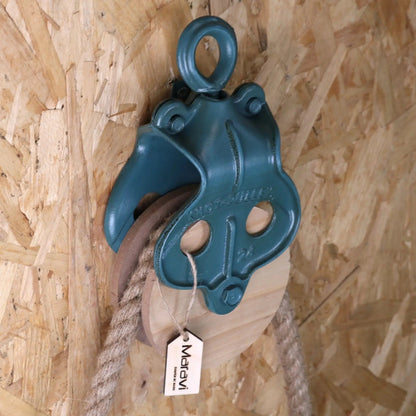 Teal pulley system attached to a rope on a wooden background