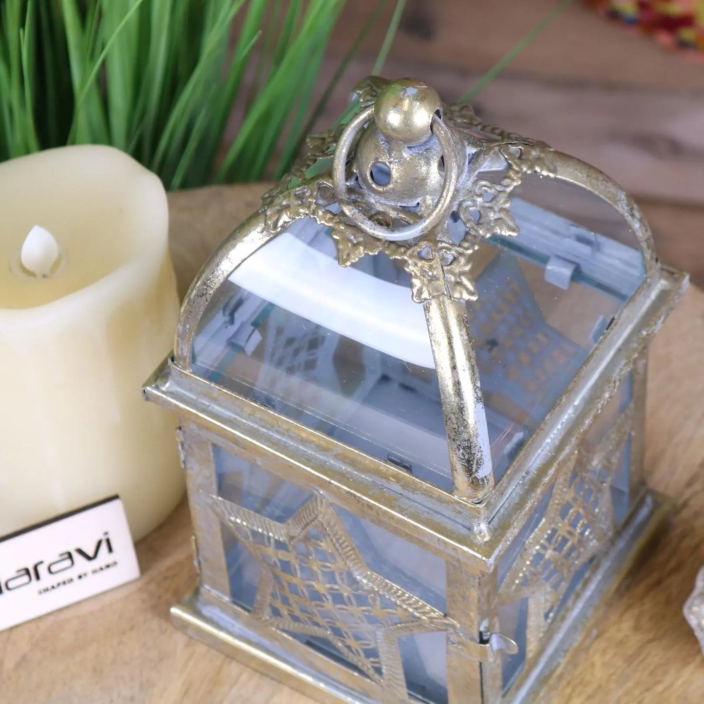 Decorative silver lantern with a candle inside, placed on a wooden surface.