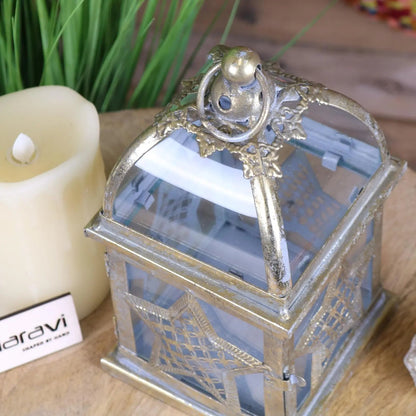 Decorative silver lantern with a candle inside, placed on a wooden surface.