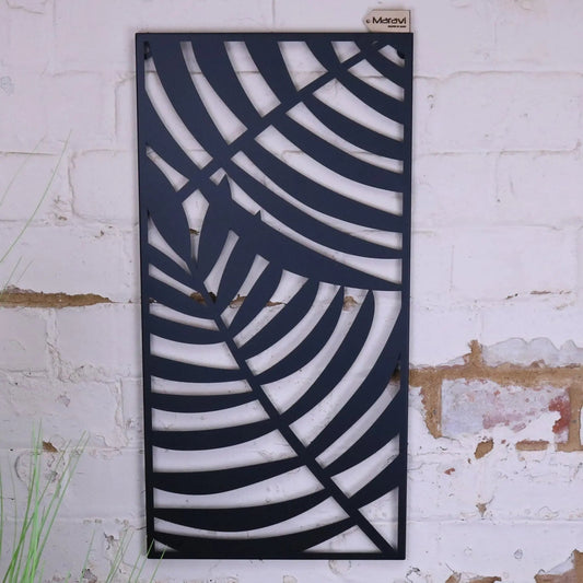 Decorative metal panel with leaf pattern on a textured white wall