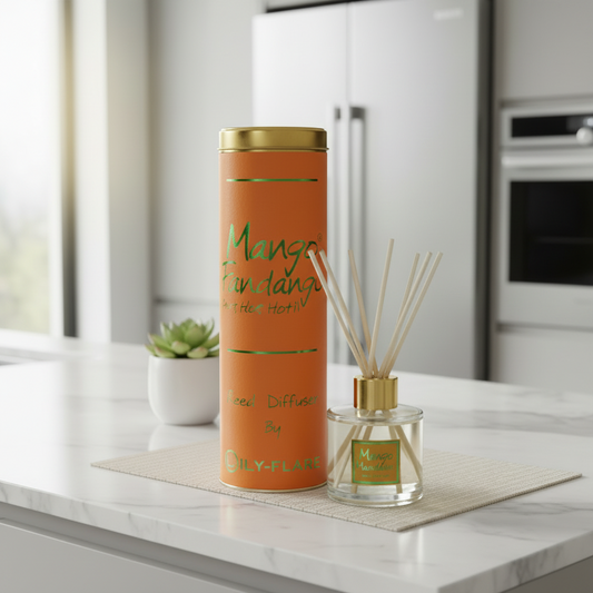 An orange reed diffuser set with a matching cylindrical tin container and glass bottle, styled on a marble countertop in a modern kitchen setting.