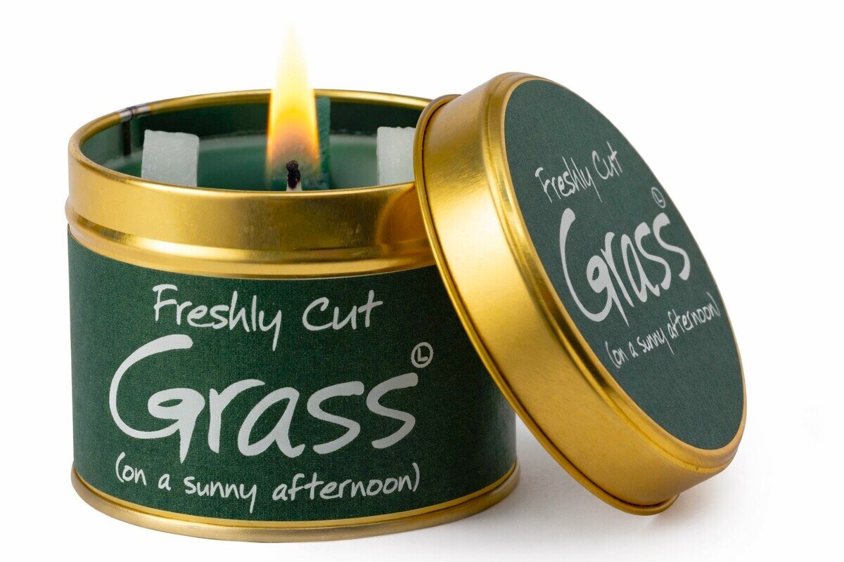 Candle in a tin labeled 'Freshly Cut Grass' with a gold lid on a white background