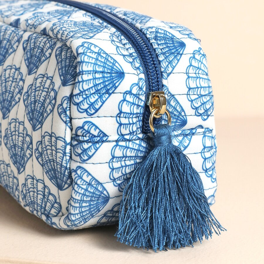 Cosmetic bag with blue shell pattern and tassel on a beige background