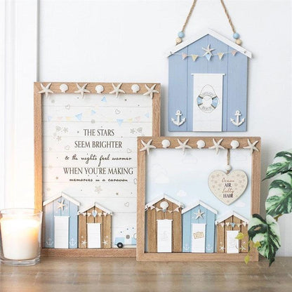 Decorative wall art with beach hut designs and text on a wooden surface.
