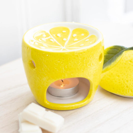 Yellow lemon-shaped candle holder with a lit tealight candle on a white surface.