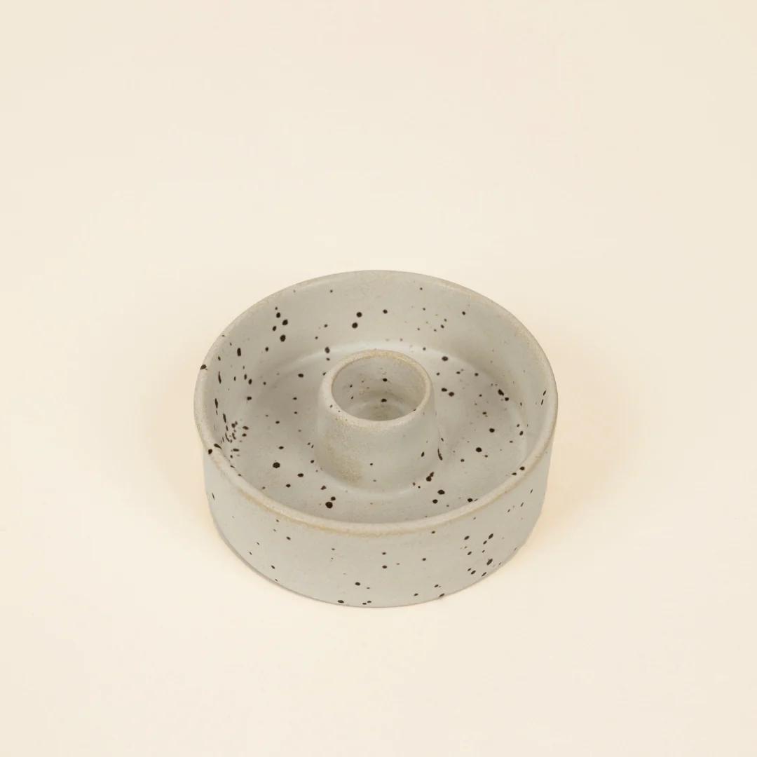 Speckled ceramic candle holder on a beige background