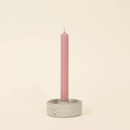 Pink candle in a speckled ceramic holder on a beige background