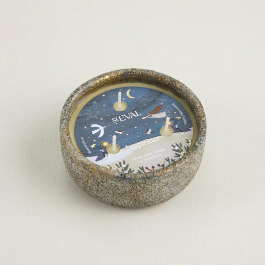 Decorative candle with a winter scene design and 'ST EVAL' branding on a light background