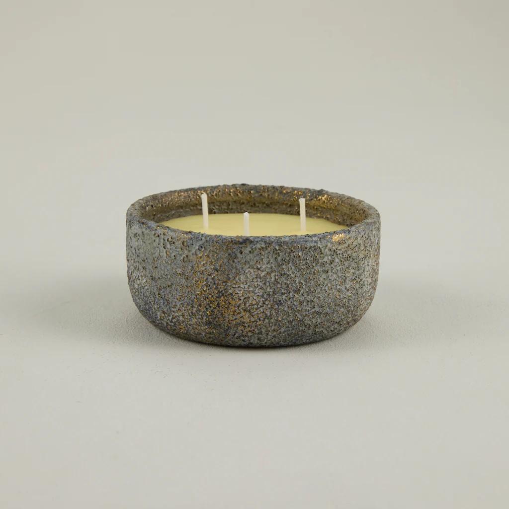 Ceramic bowl with a candle inside on a plain background
