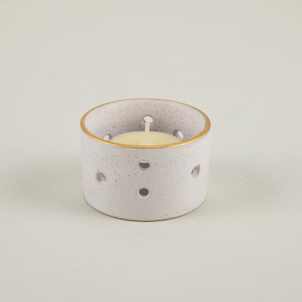 Speckled ceramic candle holder with a white candle on a light gray background