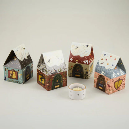 Four decorative house-shaped boxes with a small candle on a light background
