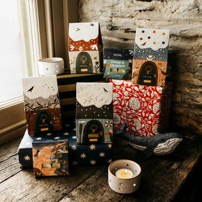 Collection of decorative boxes with various designs on a wooden surface near a window.