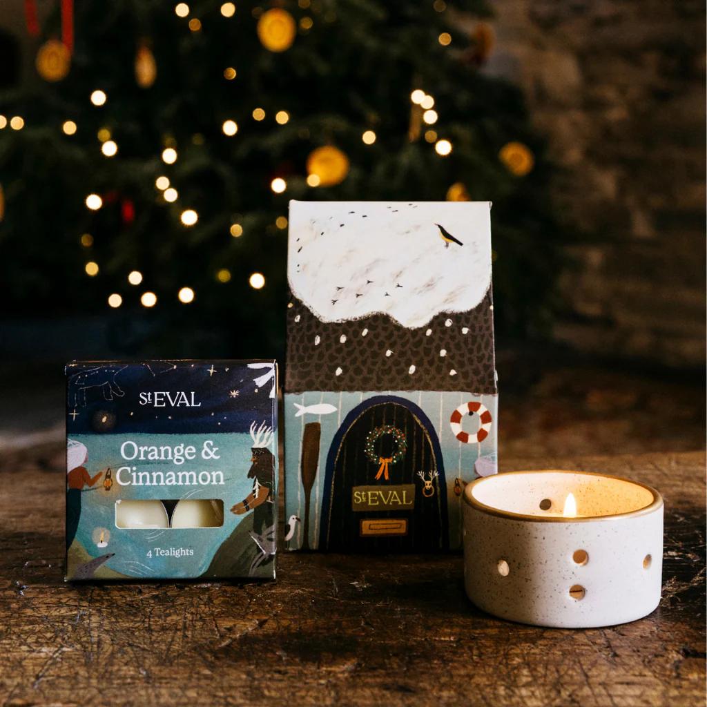 Stevale candles and packaging on a wooden surface with a Christmas tree in the background