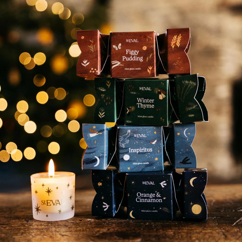 Stack of ST Eval candles with a lit candle in front, Christmas tree lights in the background