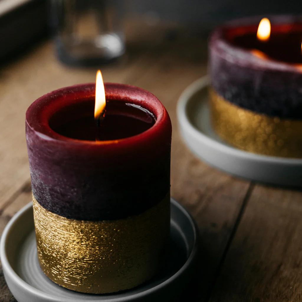 Decorative candle with gold and purple layers on a wooden surface
