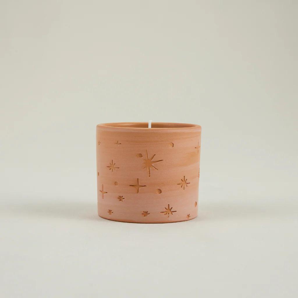Pink candle with star patterns on a light beige background