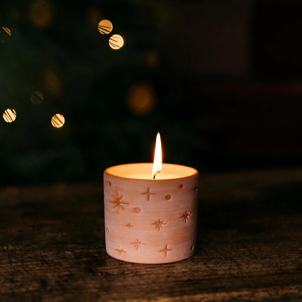 Candle in a decorative holder with a blurred Christmas tree in the background