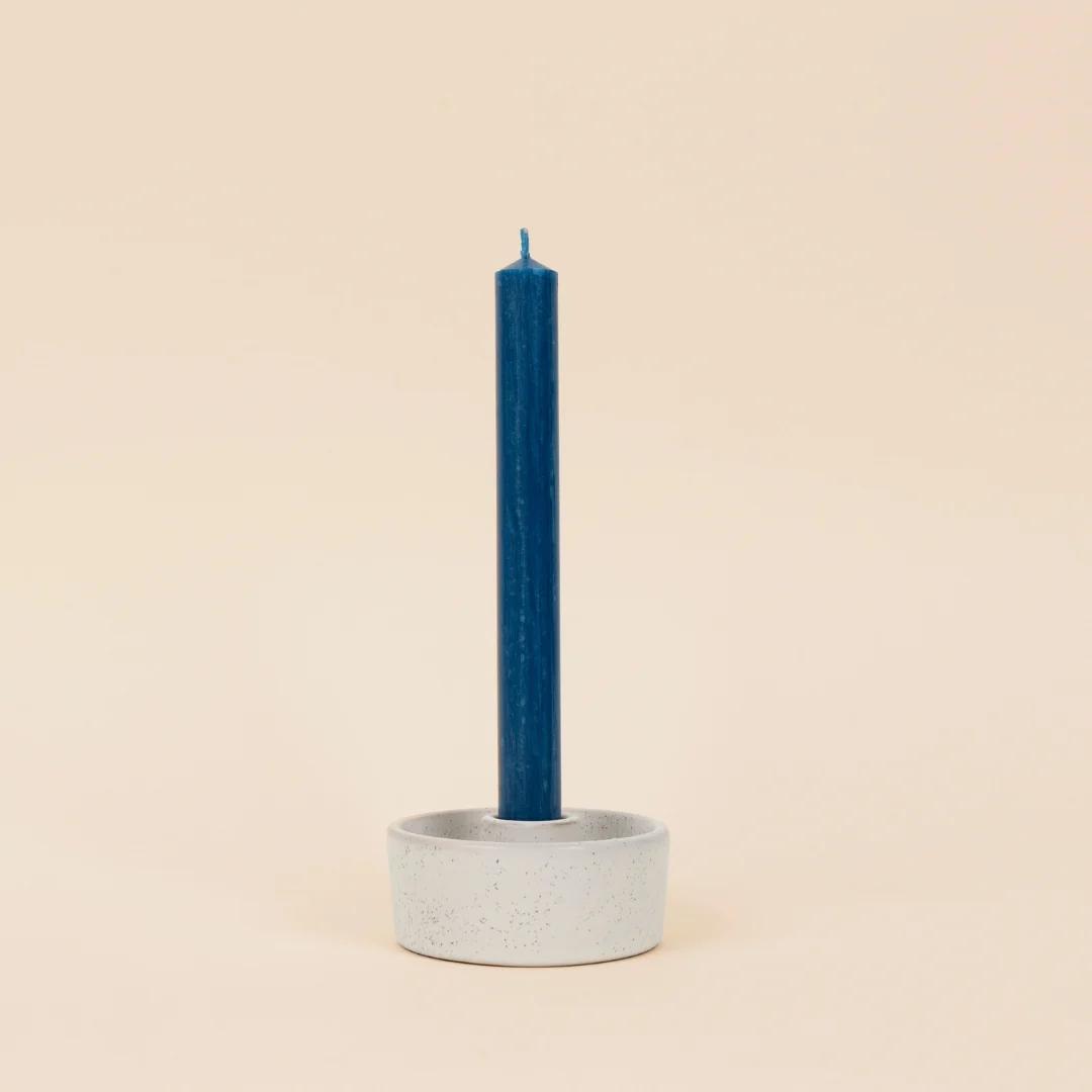 Cement candle holder with a blue candle on a beige background