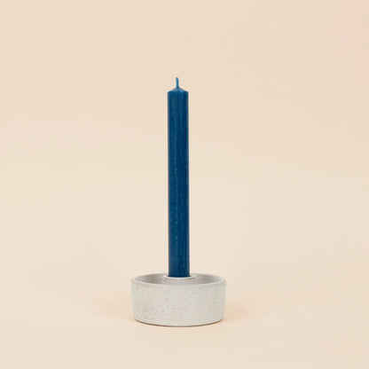 Cement candle holder with a blue candle on a beige background