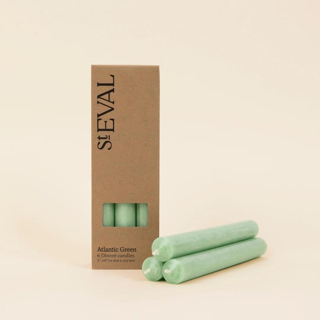 Three green candles in front of a cardboard box with 'ST EVAL' branding on a beige background