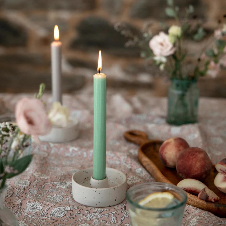 Candle in a holder on a table with peaches and flowers
