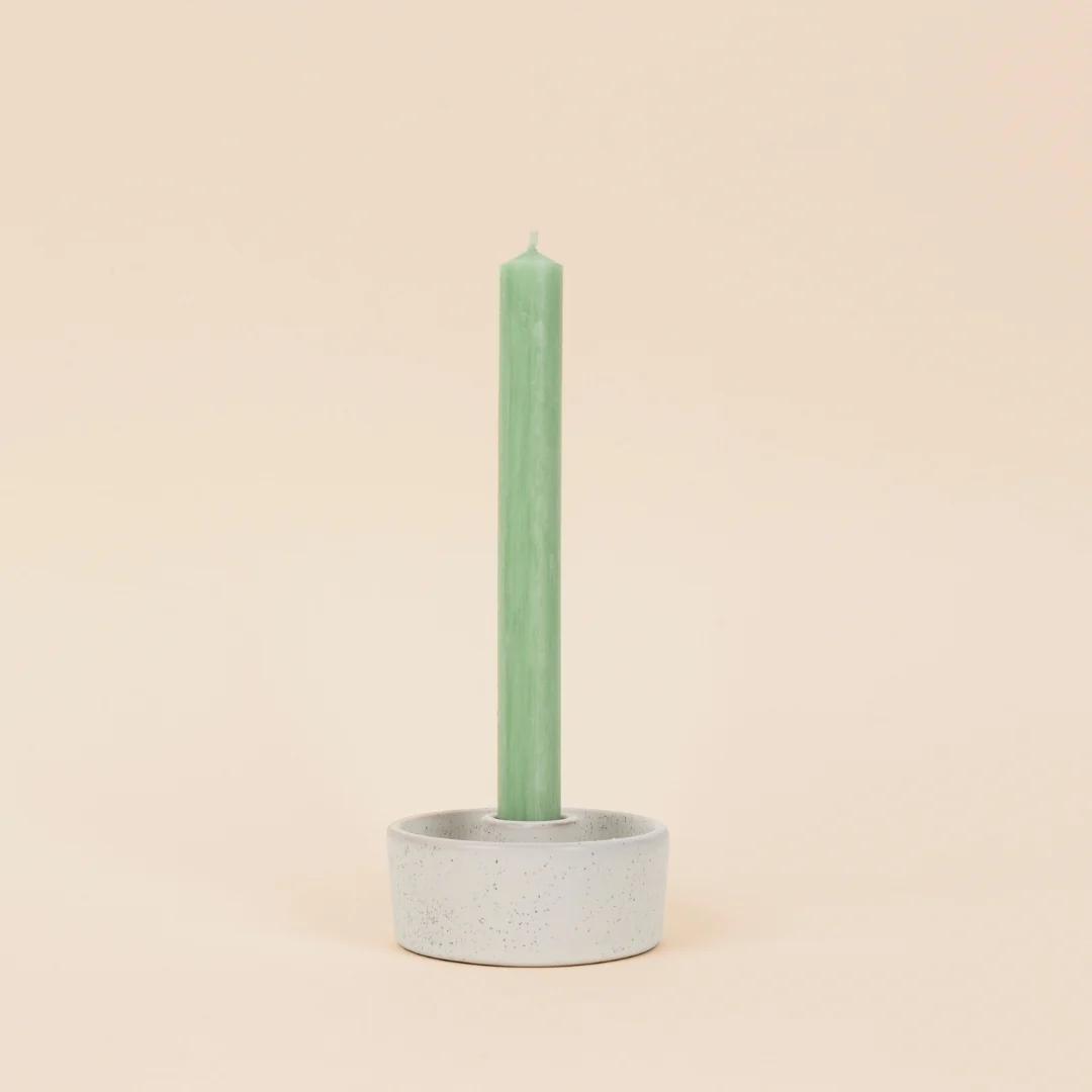 Green candle in a concrete holder on a beige background