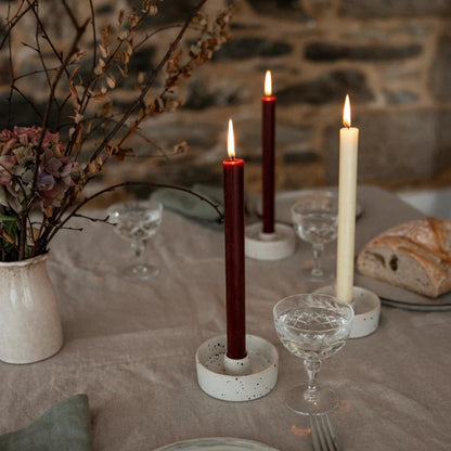 Candlelit table setting with candles, glasses, and bread on a stone wall background