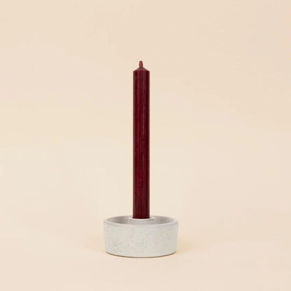 Ceramic candle holder with a red candle on a beige background