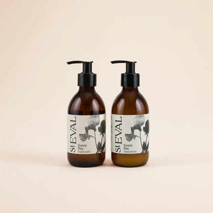 Two brown bottles with black pumps and floral labels on a beige background