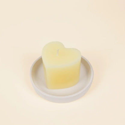 Heart-shaped candle on a white plate with a beige background