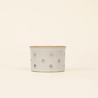 Ceramic planter with gold polka dot pattern on a beige background