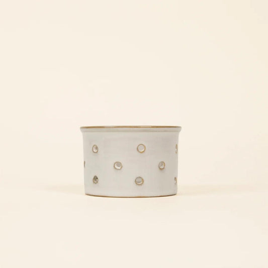 Ceramic planter with gold polka dot pattern on a beige background