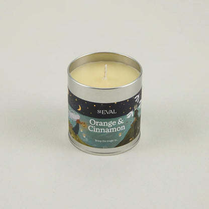 Candle in a tin labeled 'Orange & Cinnamon' by ST Eval on a light gray background