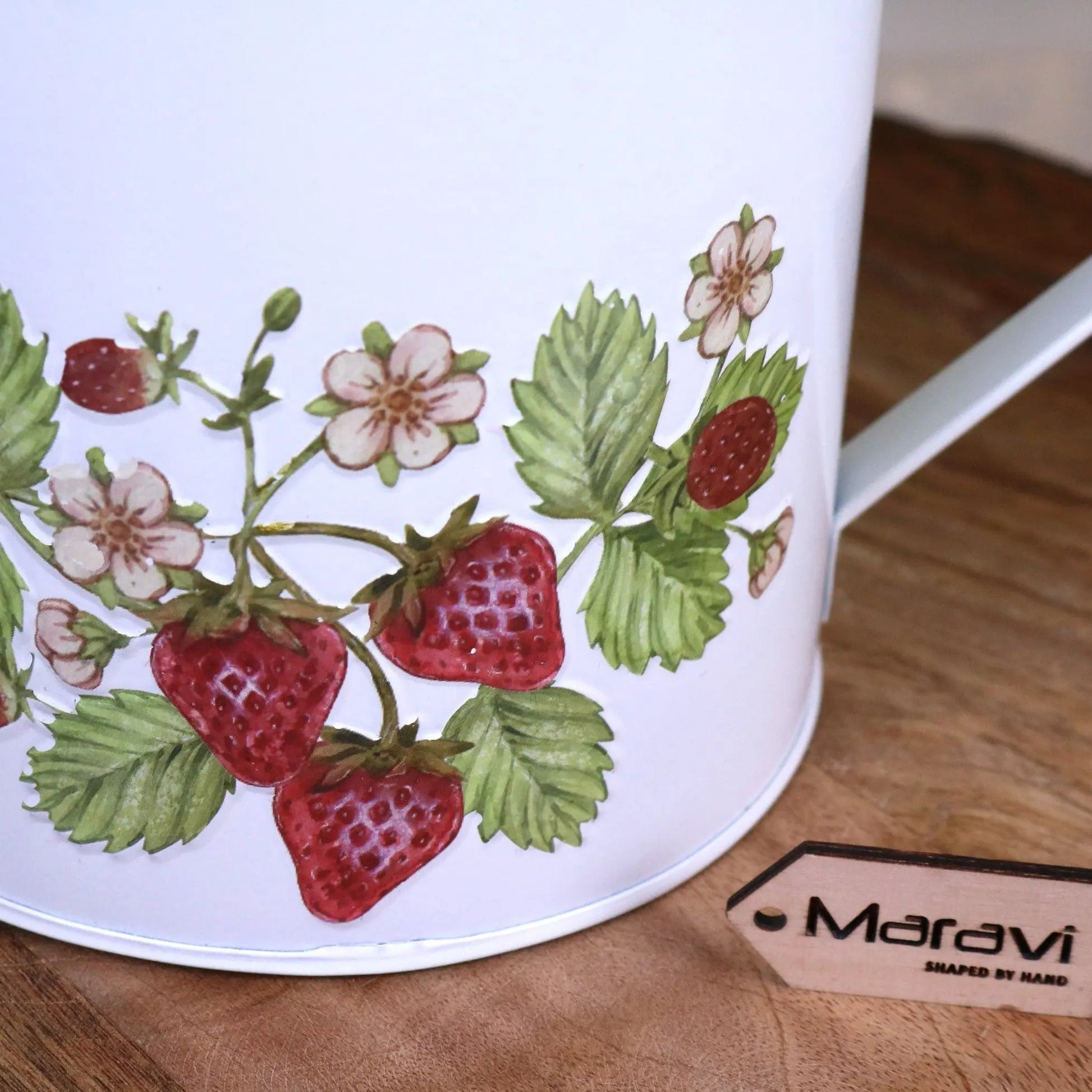 White mug with strawberry design on a wooden surface, featuring the brand 'Maravi'.