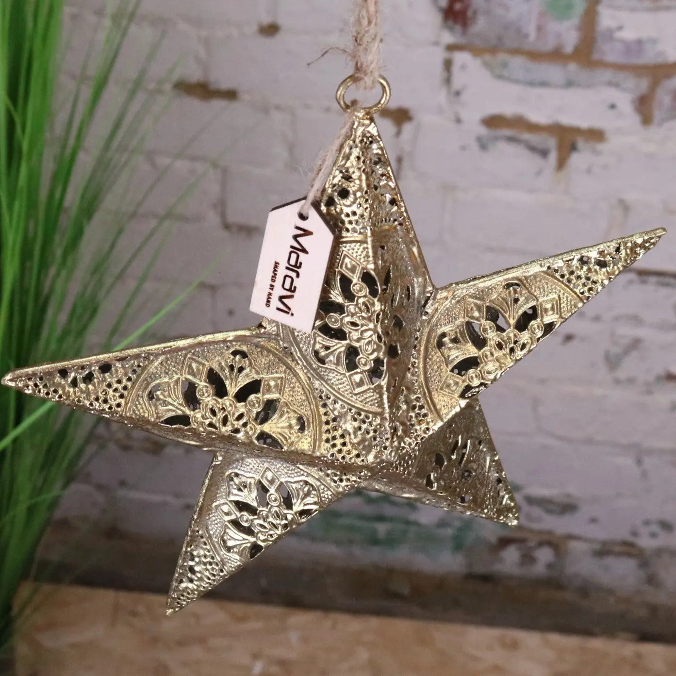 Decorative gold star ornament with a visible brand tag against a rustic background