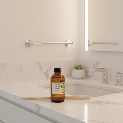 An amber glass bottle labeled 'Osmothic Citrus Tonic' sits on a white marble bathroom counter next to a sink, with a small plant and chrome faucet in the background.